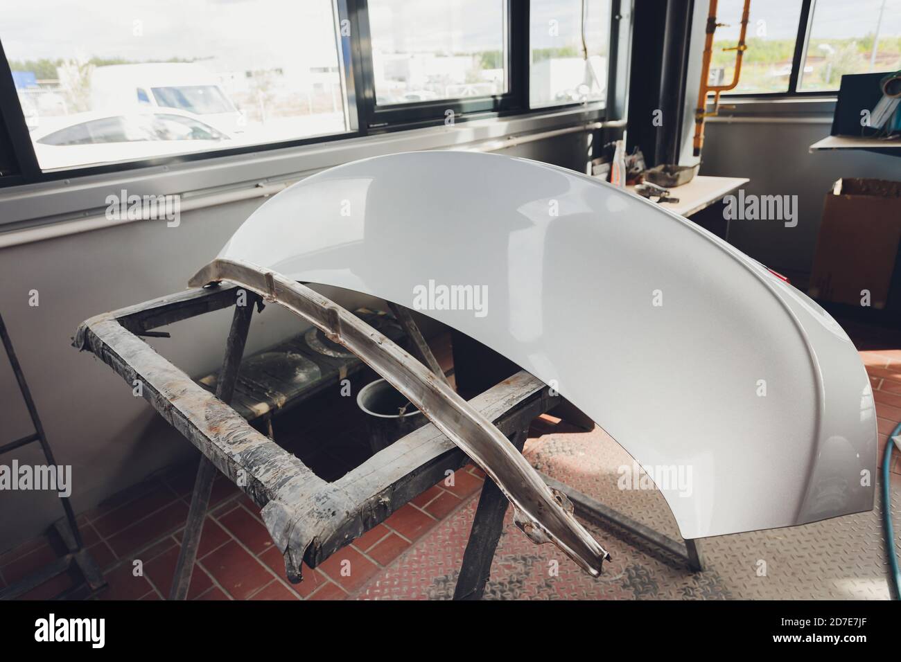 Auto bumper part is installed on the racks after painting in car repair