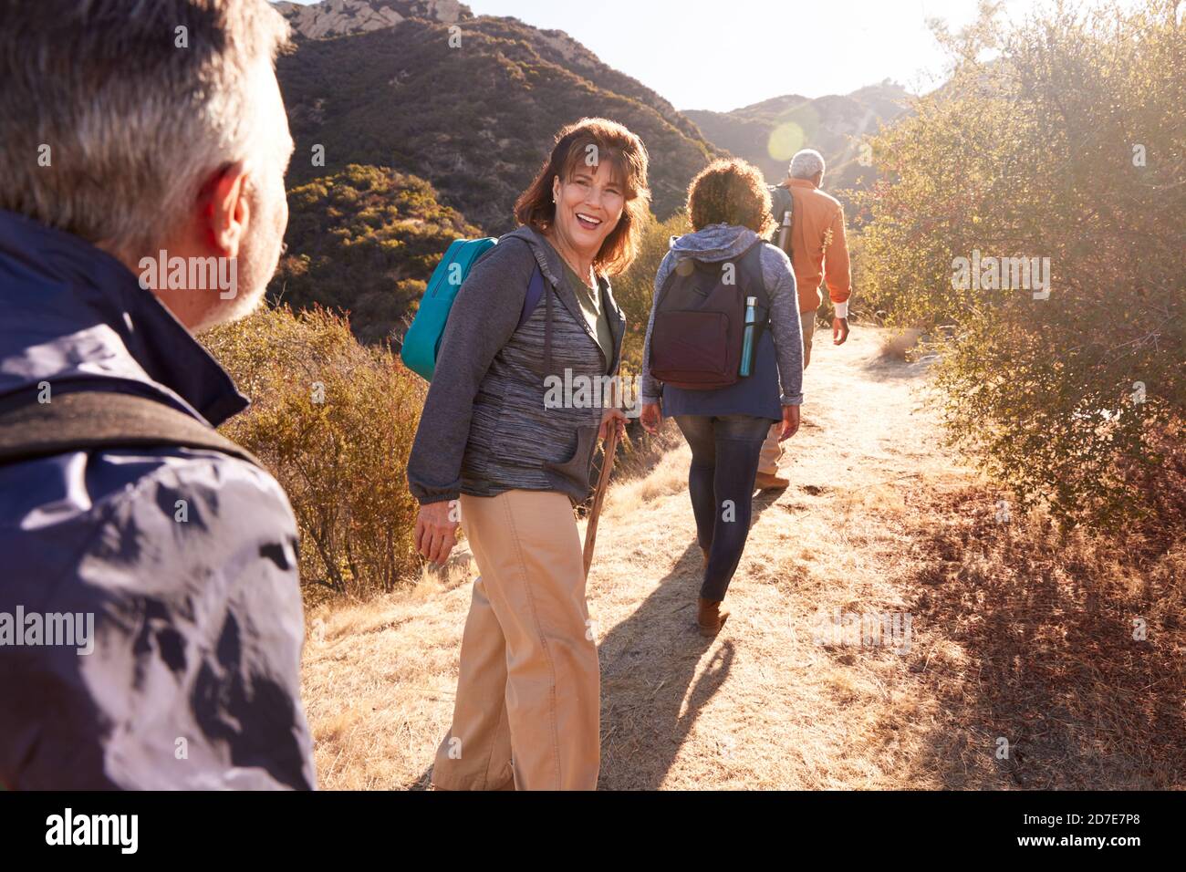 Group Of Senior Friends Go Hiking Along Trail In Countryside Together Stock Photo