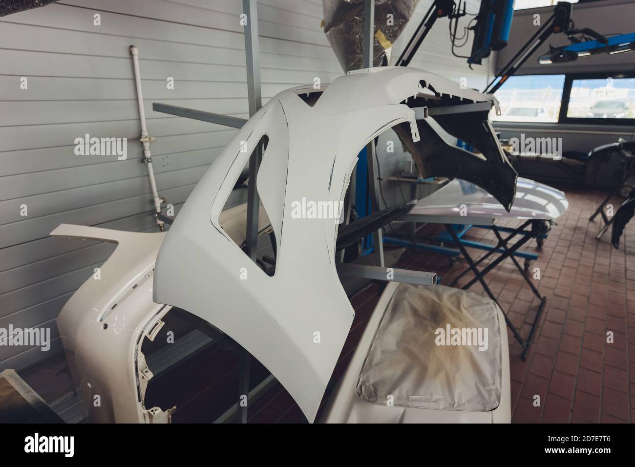 Auto bumper part is installed on the racks after painting in car repair