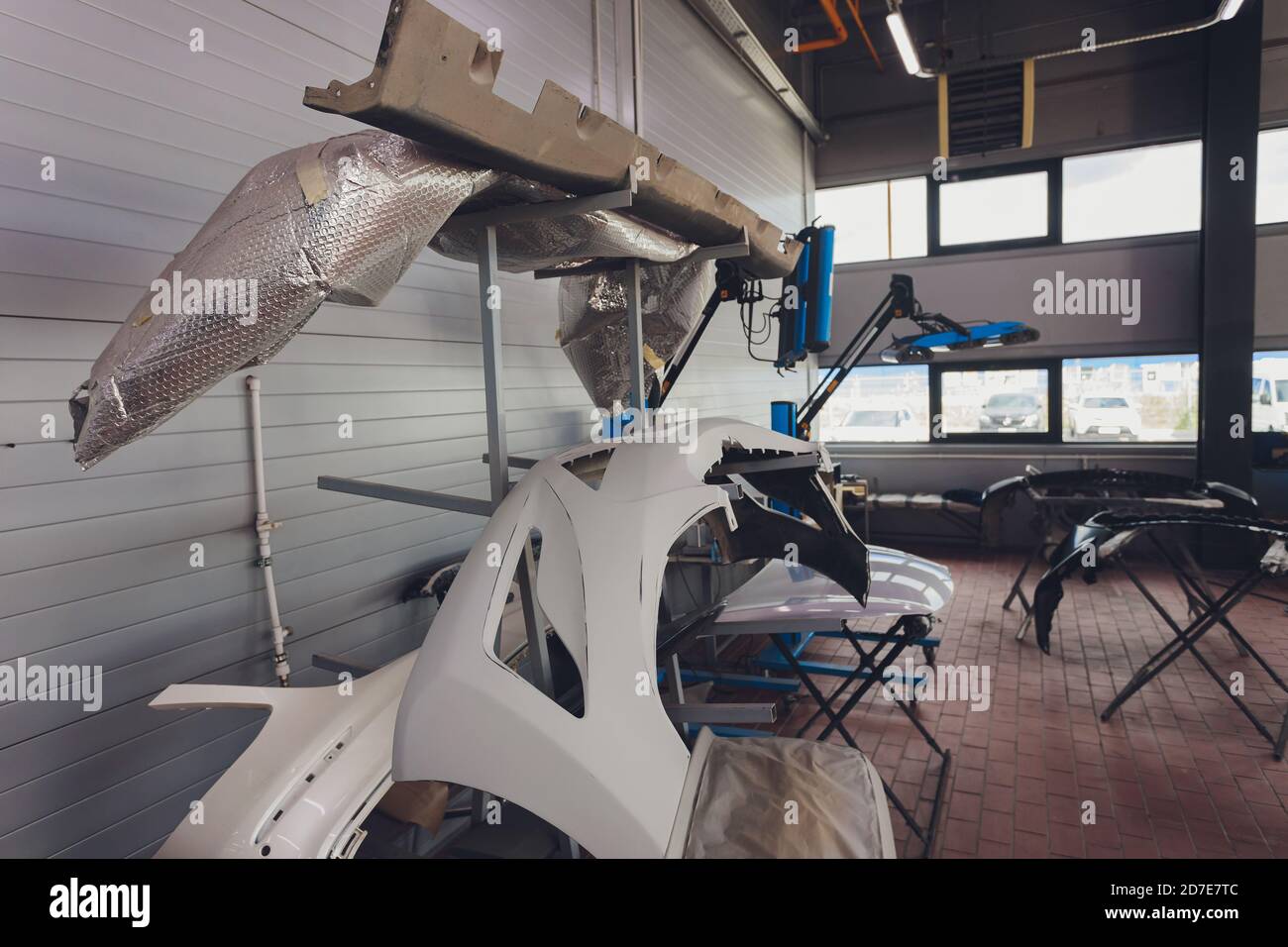 Auto bumper part is installed on the racks after painting in car repair shop. Stock Photo