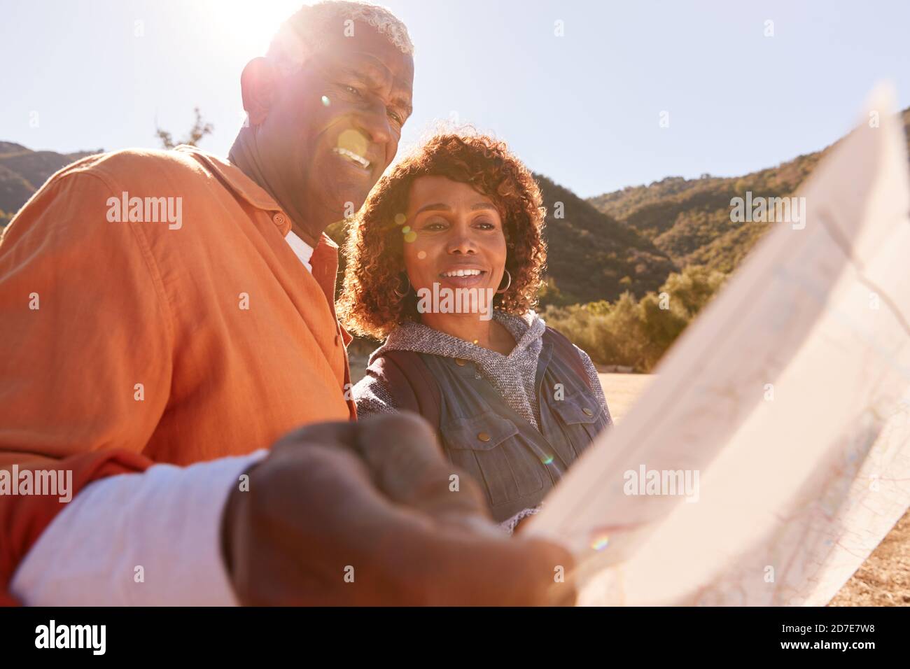 Senior Couple Looking At Map As They Hike Along Trail In Countryside Together Stock Photo