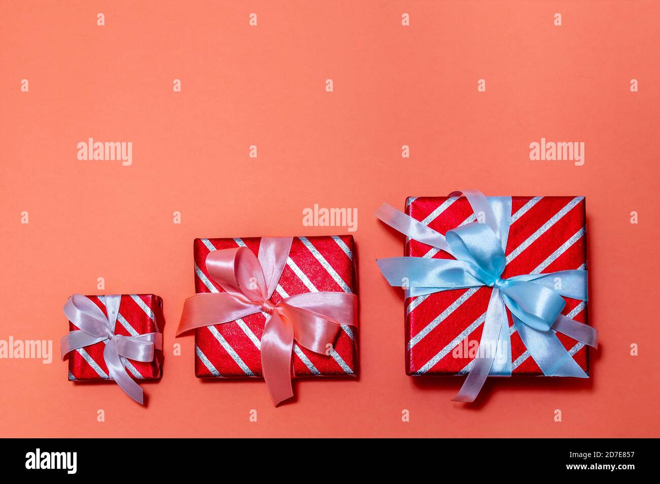 Creative Christmas Composition with Three Gift Boxes on Red Background. Top View Flat Lay. Stock Photo