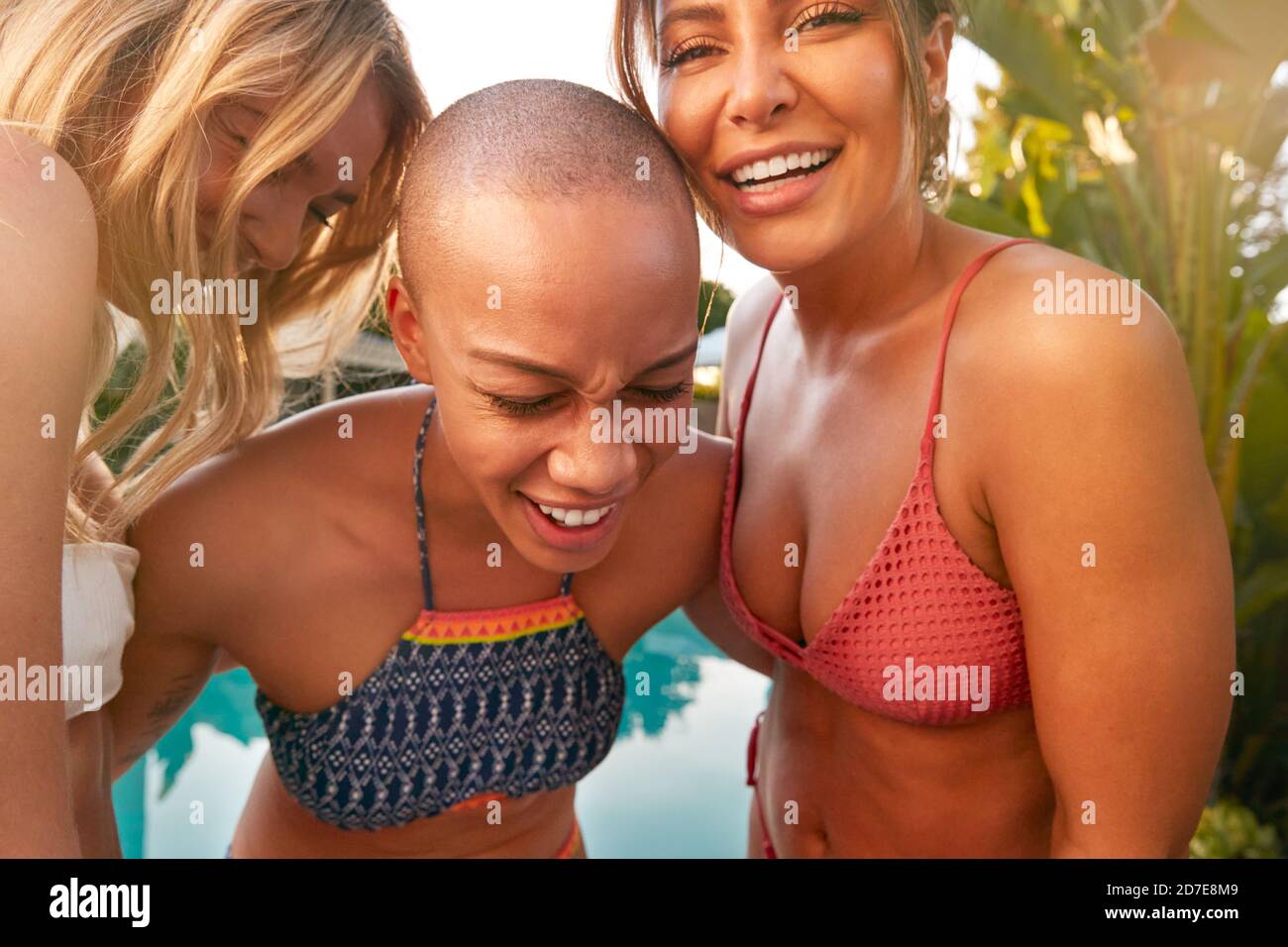 Three Female Friends Outdoors Relaxing In Swimming Pool And Enjoying Summer Party Stock Photo
