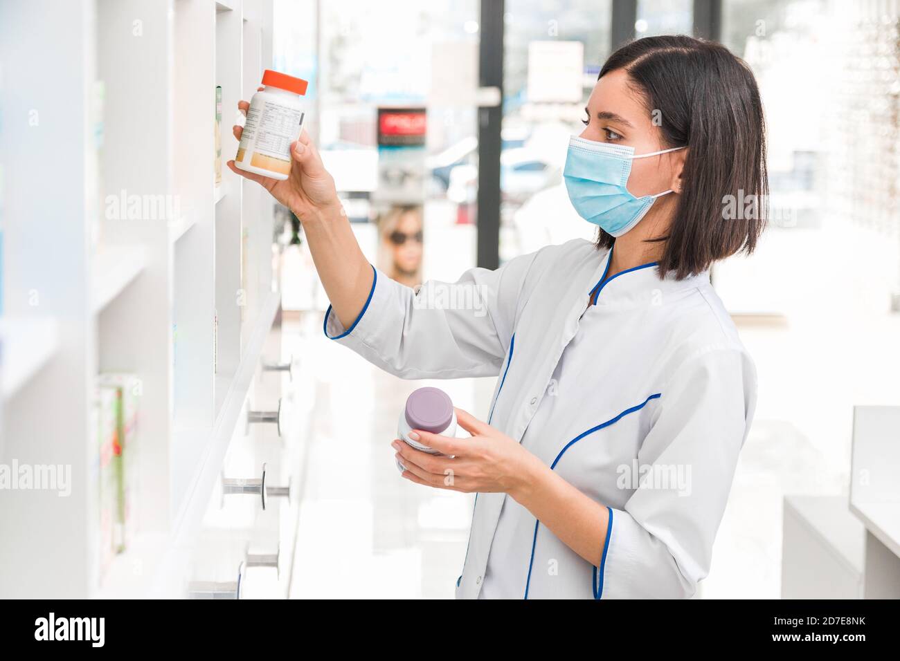 choosing the right medicine. professional looking female pharmacist with medical mask on in drug store studying the prospectus of a new drug Stock Photo