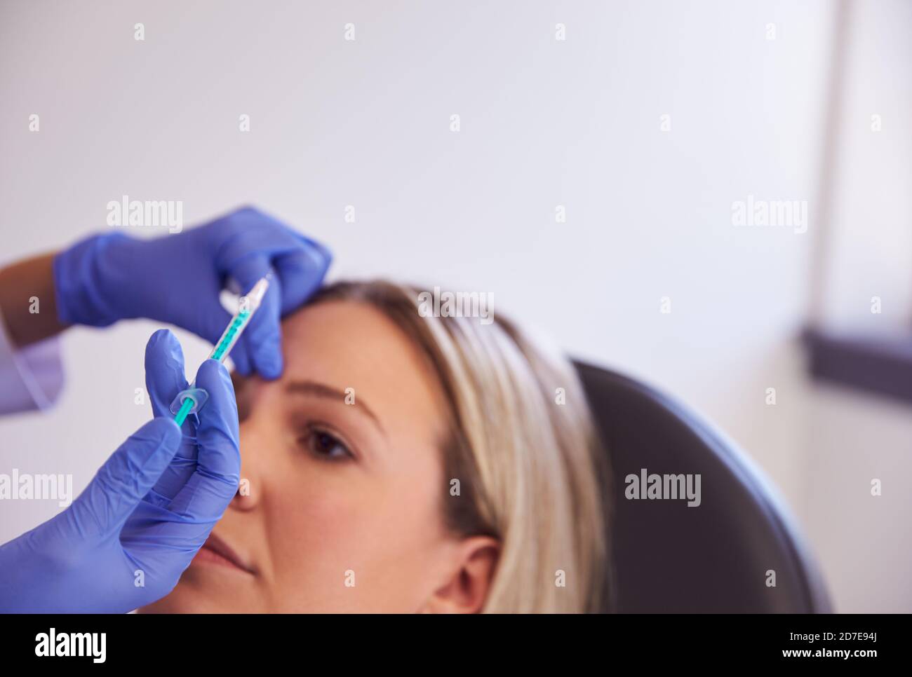 Woman Sitting In Chair Being Give Botox Injection In Forehead By Female ...