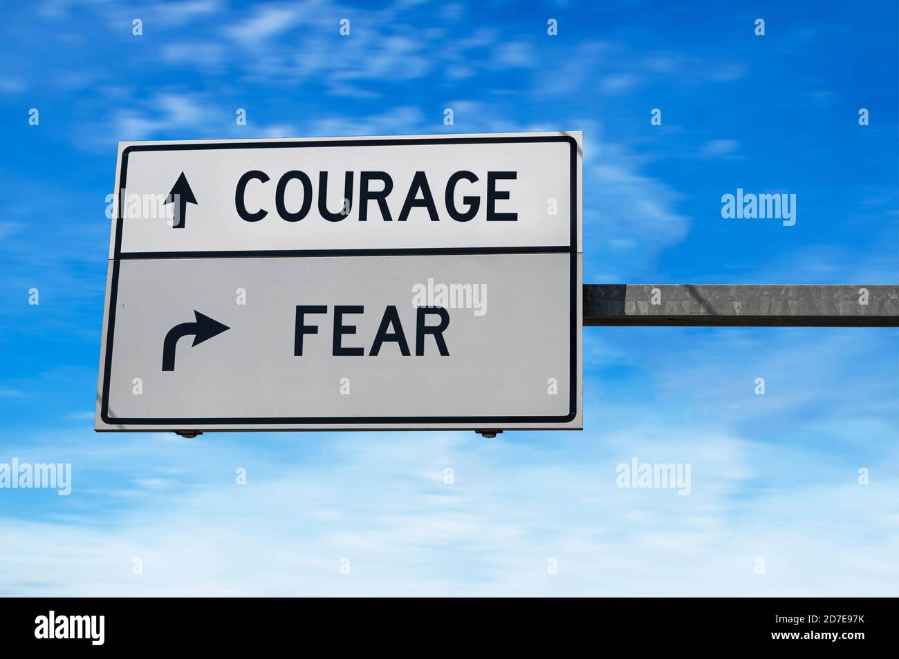 Courage versus fear. White two street signs with arrow on metal pole. Directional road. Crossroads Road Sign, Two Arrow. Blue sky background. Stock Photo
