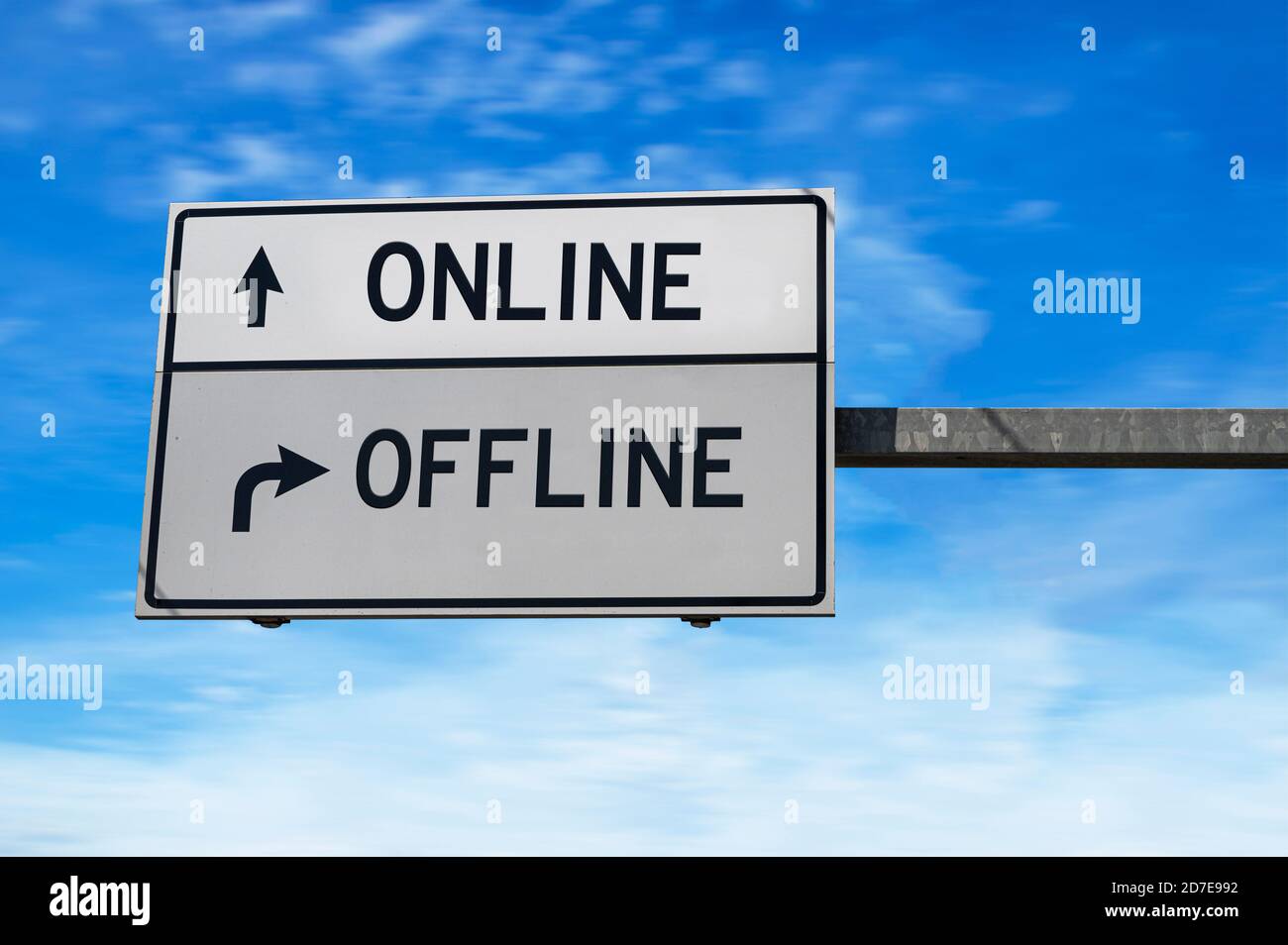 Online versus offline. White two street signs with arrow on metal pole. Directional road. Crossroads Road Sign, Two Arrow. Blue sky background. Stock Photo