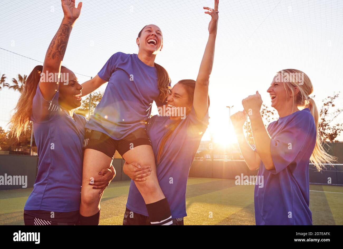 Womens Football Team Celebrating Winning Soccer Match Lifting Player Onto Shoulders Stock Photo