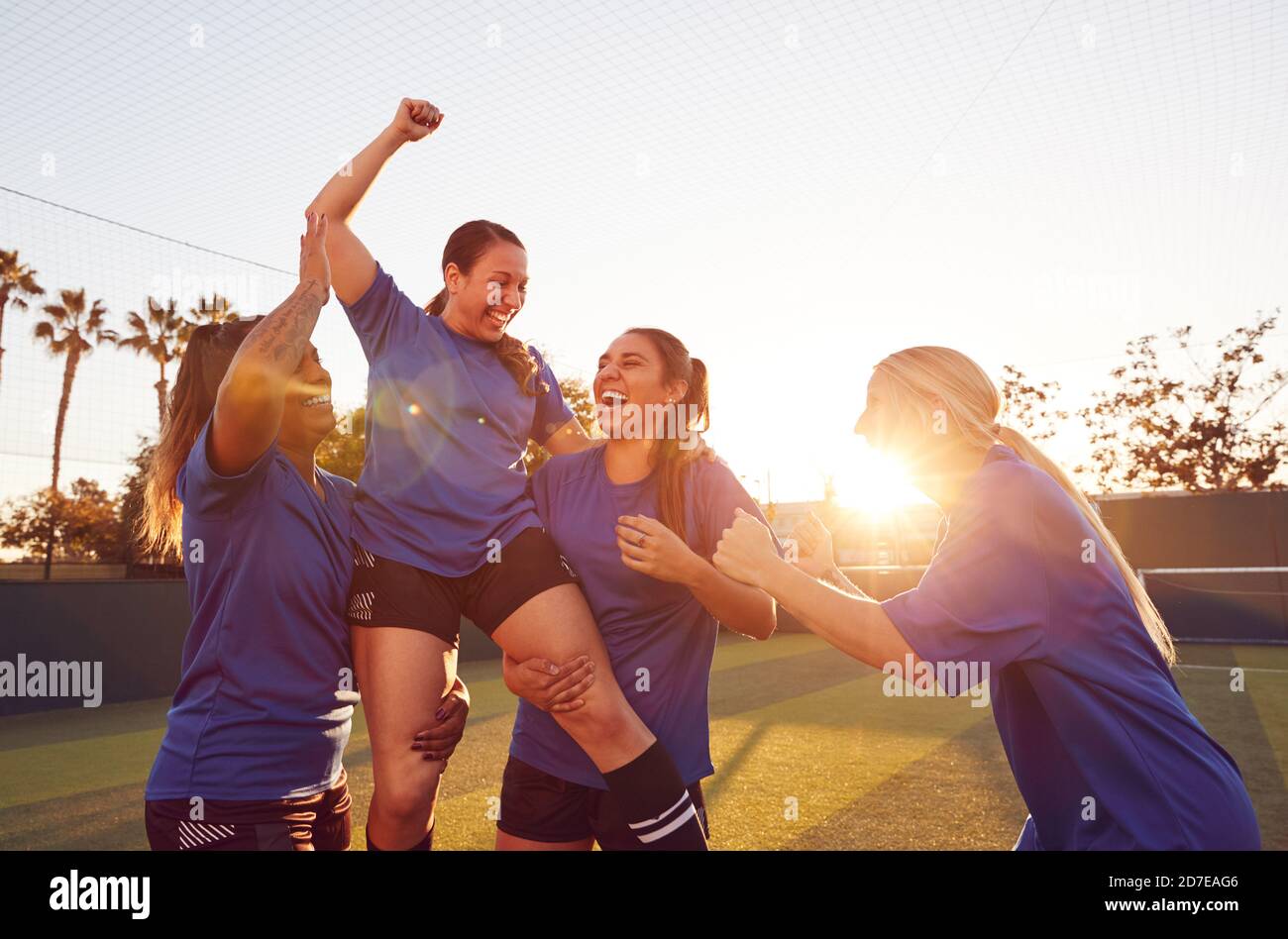 Womens Football Team Celebrating Winning Soccer Match Lifting Player Onto Shoulders Stock Photo