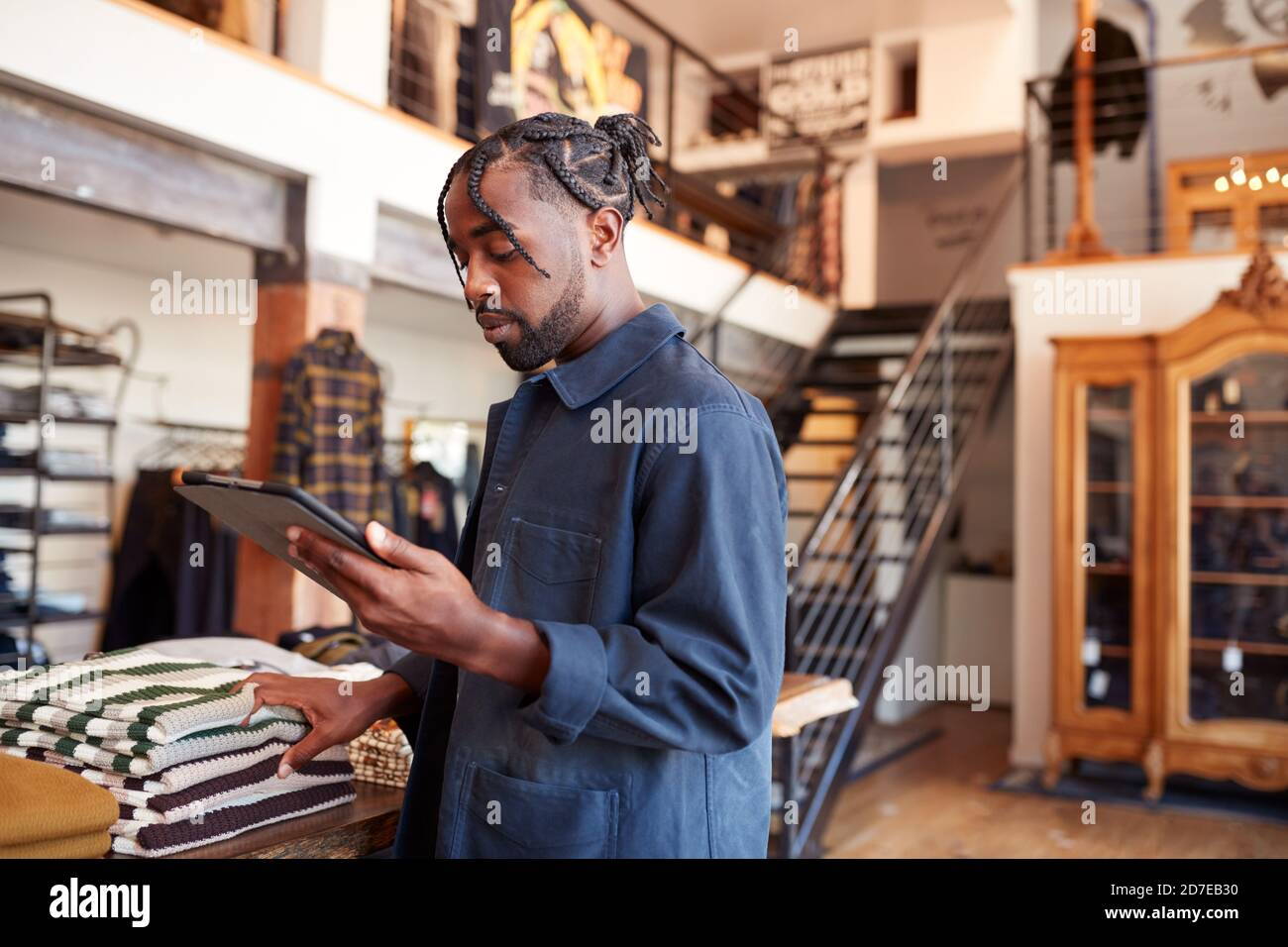 Male Owner Of Fashion Store Using Digital Tablet To Check Stock In Clothing Store Stock Photo