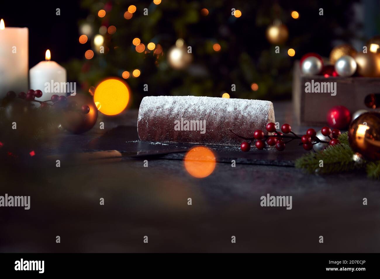 Traditional Yule Log On Table Set For Festive Christmas Meal With Tree