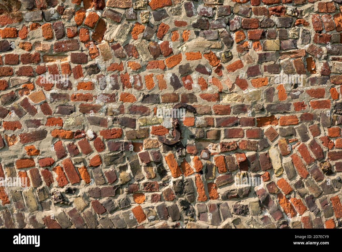A section of antique red brick wall with random construction and including wrought iron S anchor plate Stock Photo