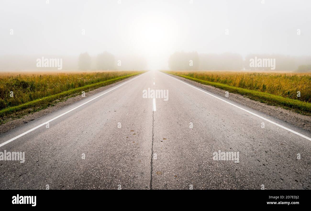 Morning on the road among the fields and fog Stock Photo - Alamy