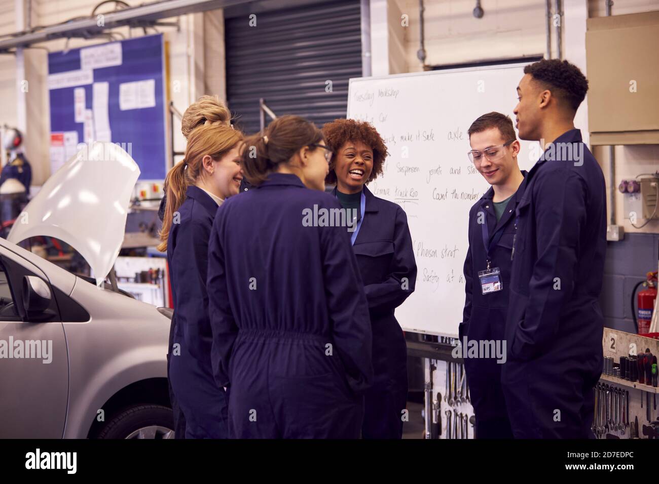 Students Studying For Auto Mechanic Apprenticeship At College Standing By Whiteboard Stock Photo