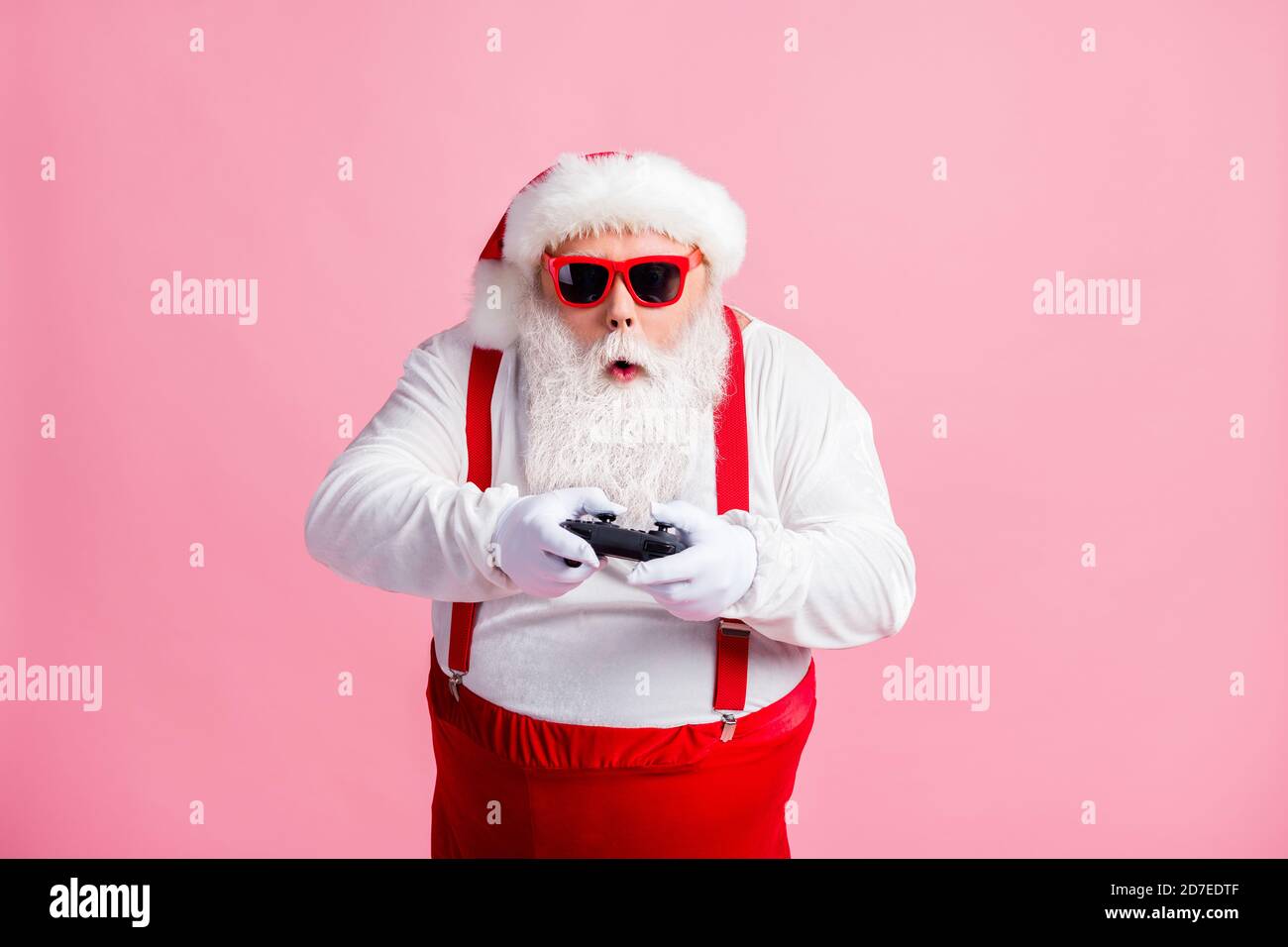 Portrait of his he nice funny focused bearded fat guy Santa hipster using gadget playing game station psp spending free time contest isolated pink Stock Photo