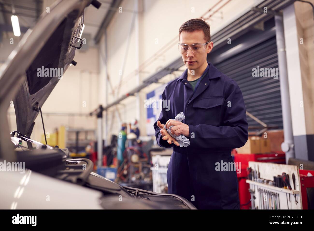 Male Motor Mechanic Wiping Hands After Working On Car Engine In Garage Stock Photo