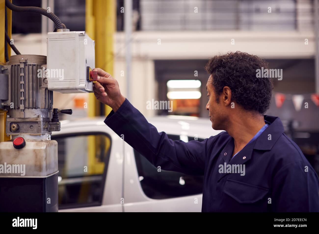 Male Motor Mechanic Raising Car On Hydraulic Lift In Garage Stock Photo