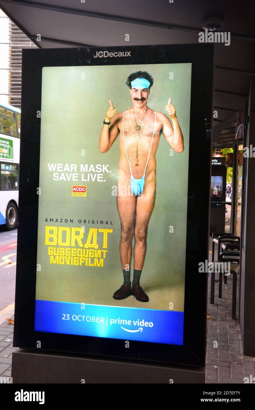 Covid 19 or coronavirus signage and advertising in Manchester, Greater Manchester, England, United Kingdom. An illuminated sign advertising a Borat film urges people to wear masks. Stock Photo