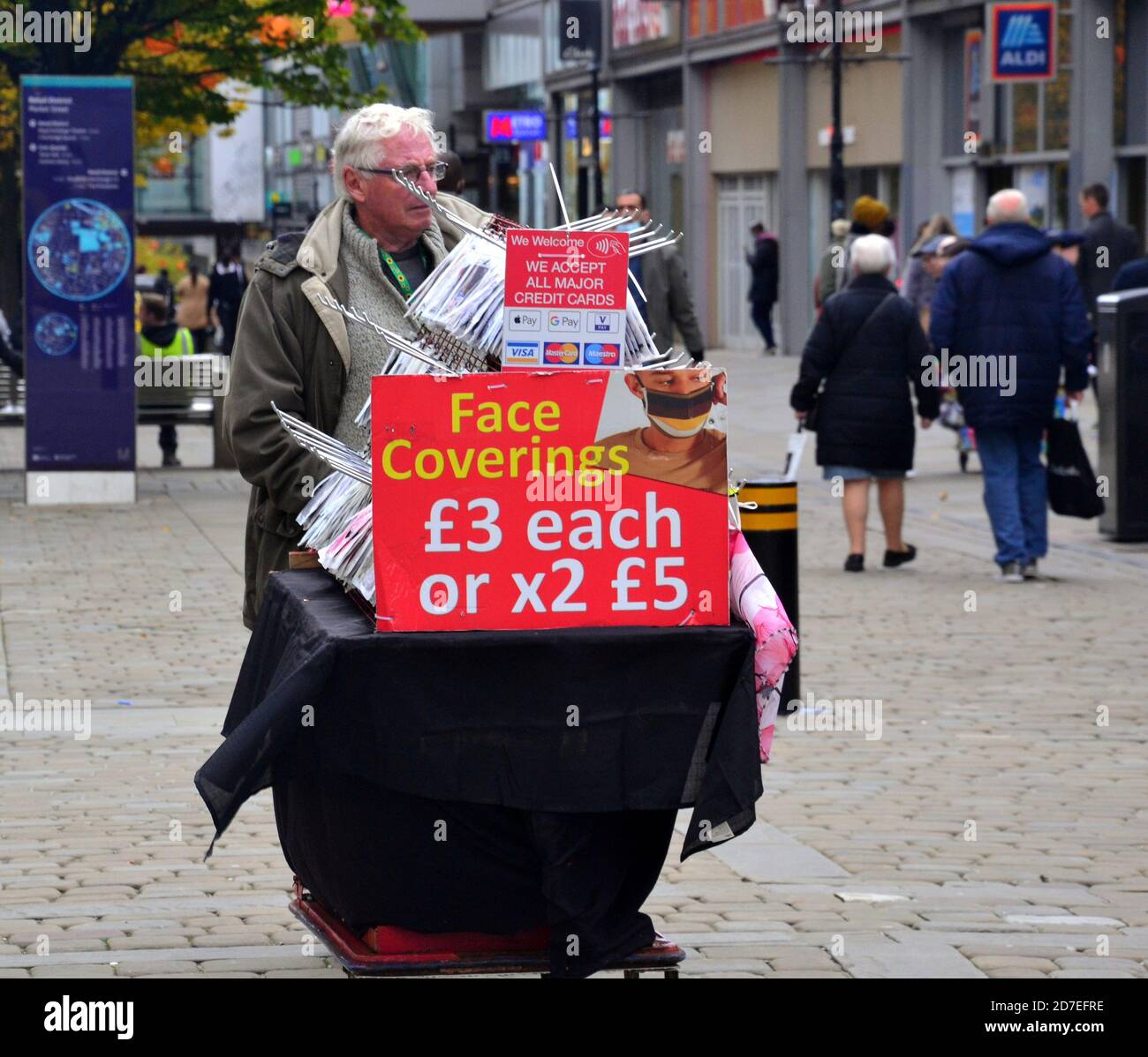 Covid 19 or coronavirus signage and advertising in Manchester, Greater Manchester, England, United Kingdom. A man sells face coverings and masks on Market Street, central Manchester. Stock Photo