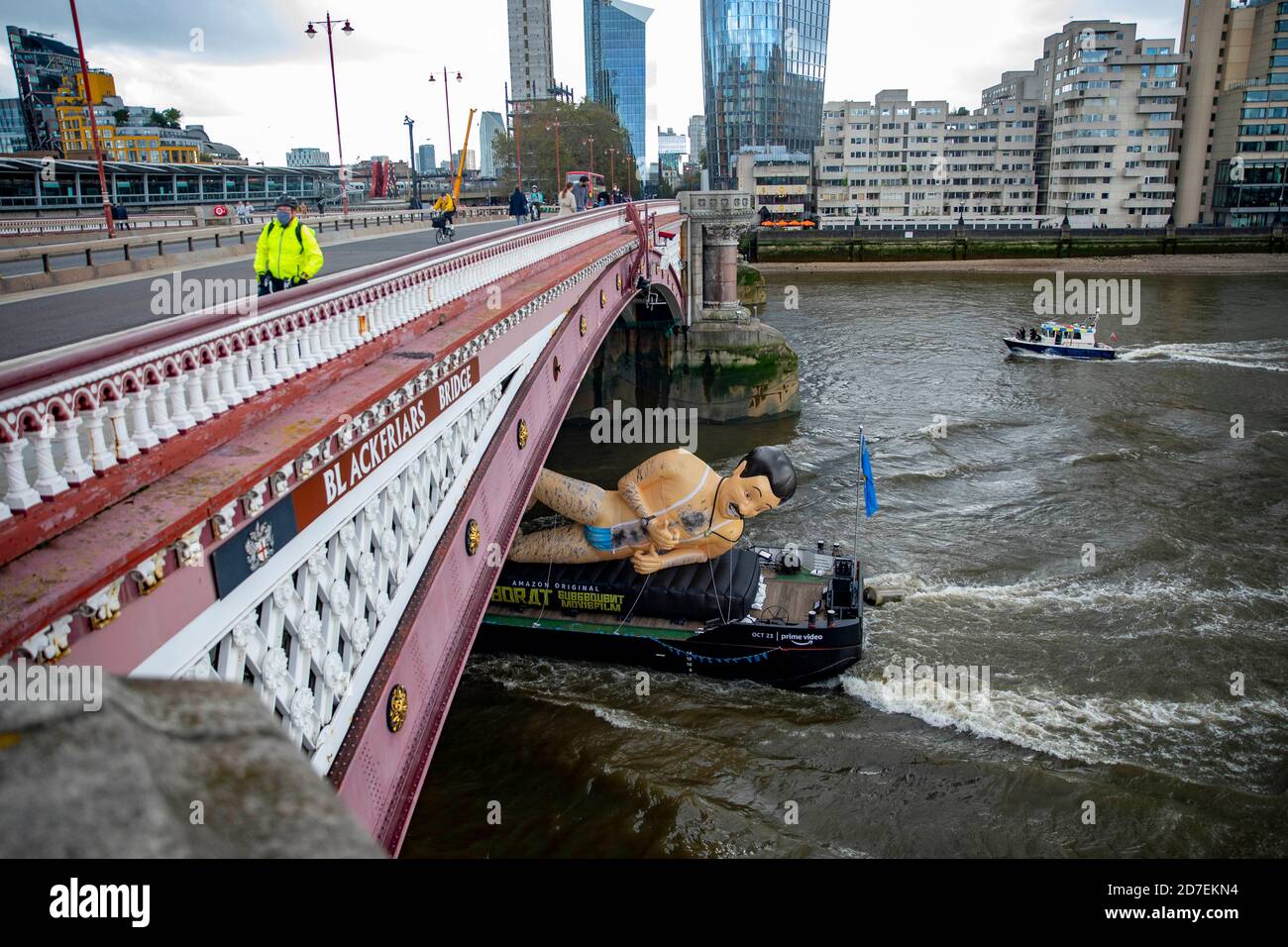pic shows:  Borat inflatable goes down the Thames in London to promote Borat 2  Masked cyclists cross Blackfriars as the inflatable goes underneath Stock Photo