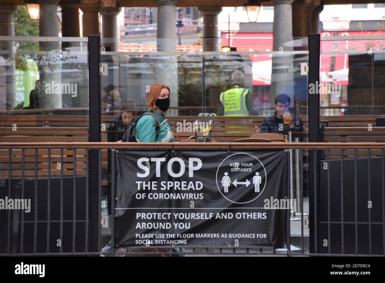 A woman with a face mask walks past a Stop The Spread Of Coronavirus sign at Covent Garden Market. London, United Kingdom 2020. Stock Photo