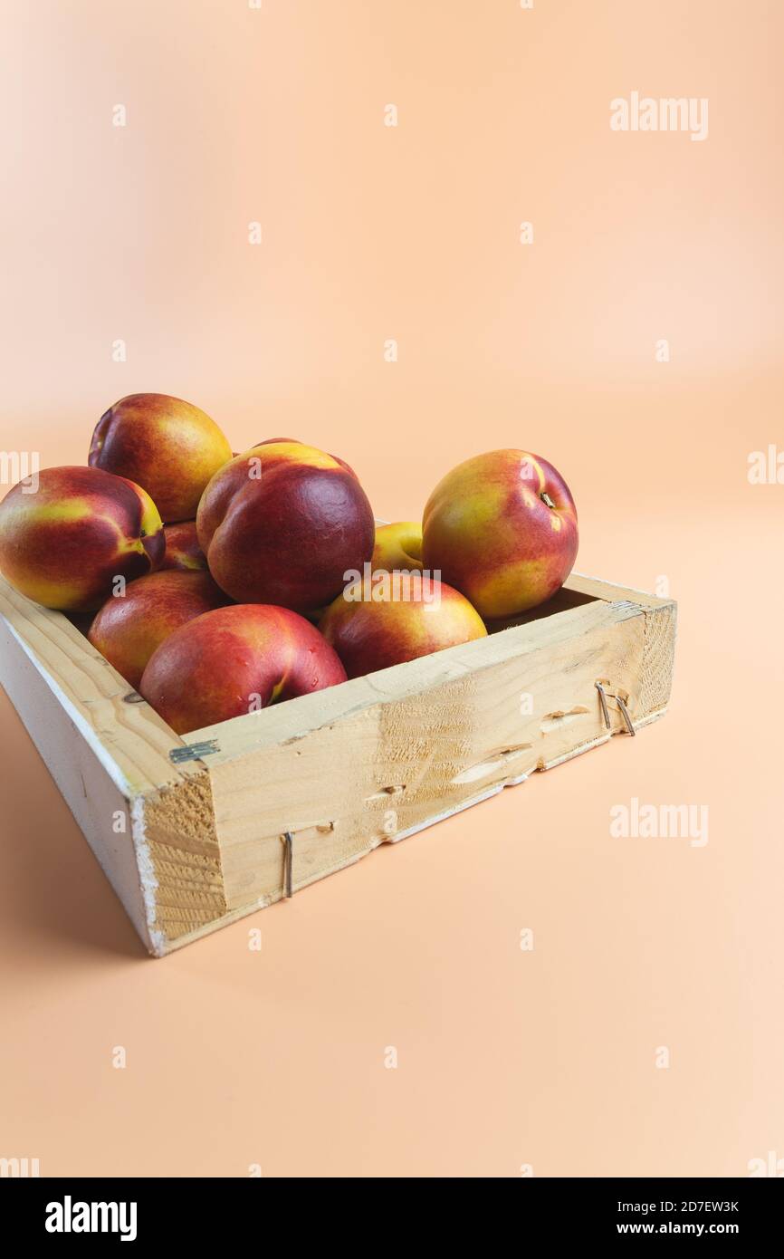 Red very ripe peaches, nectarines inside a wooden box for sale. Peachy