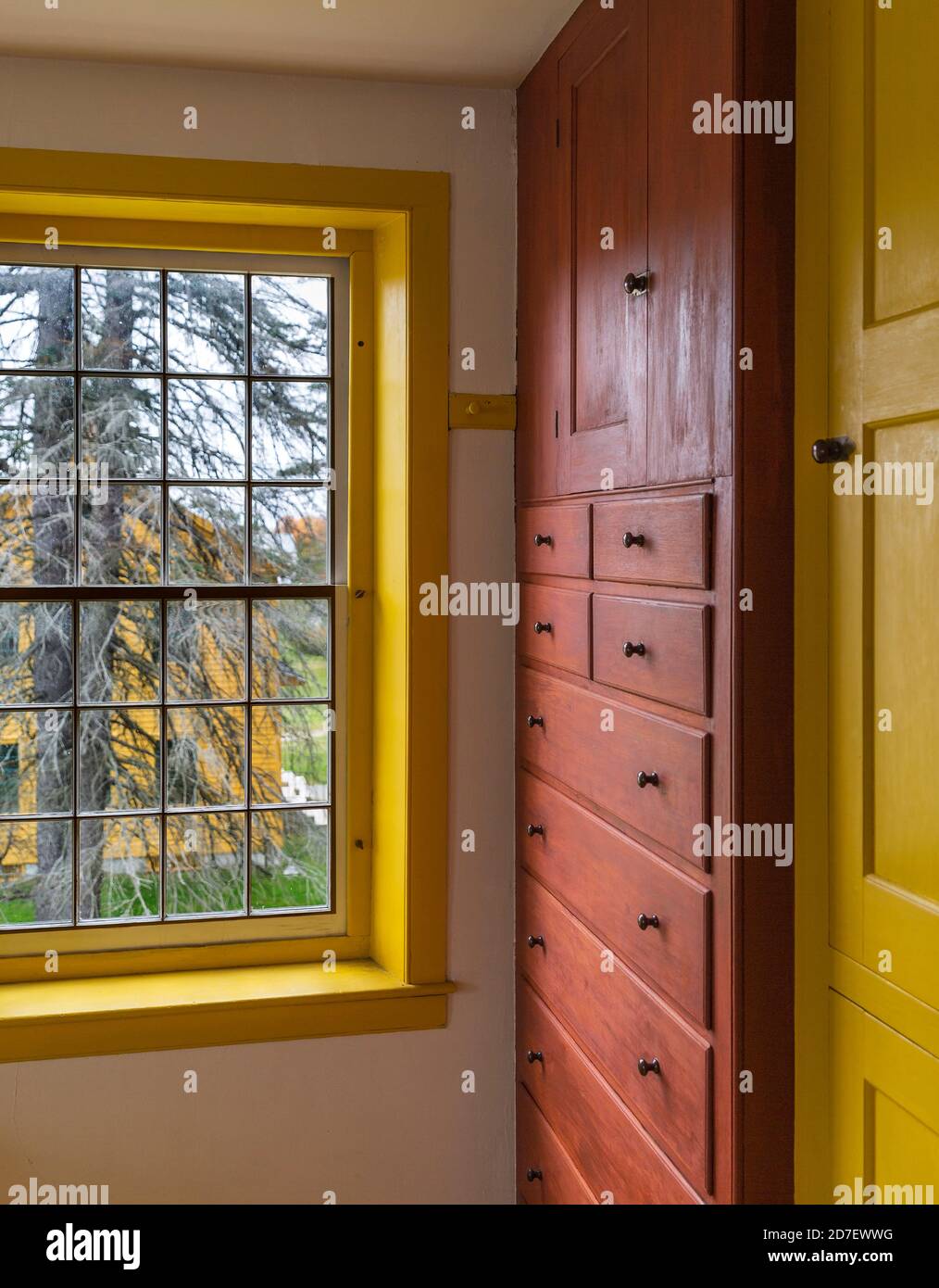 interior view of yellow window frame and mahogany cabinets in perfect harmony in a Shaker Style house Stock Photo