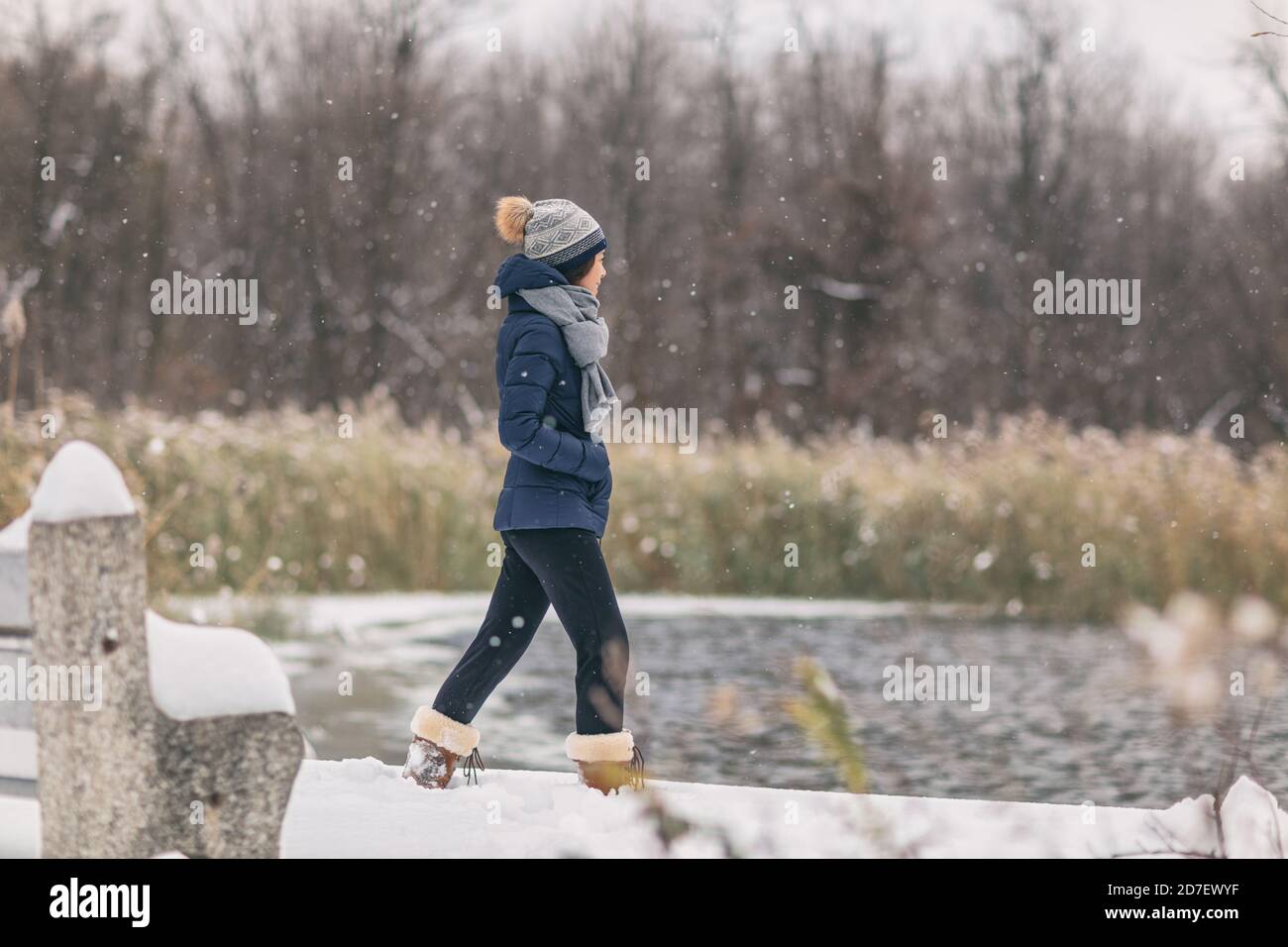 Winter snow storm happy cold weather girl walking in snowing forest woods background by the lake in cozy jacket Stock Photo