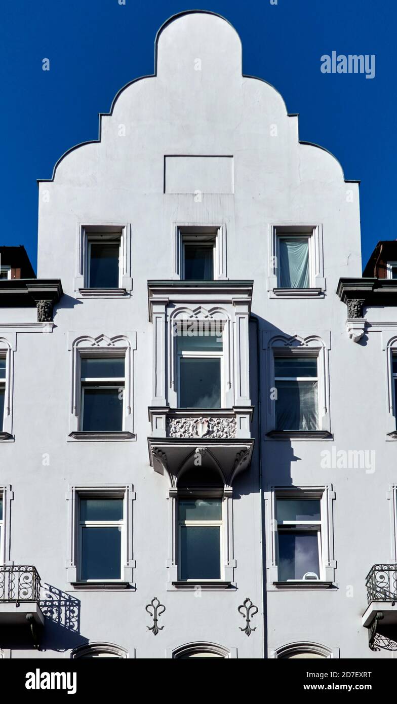 White house with decorated facade with small balcony, balustrade and gable Stock Photo