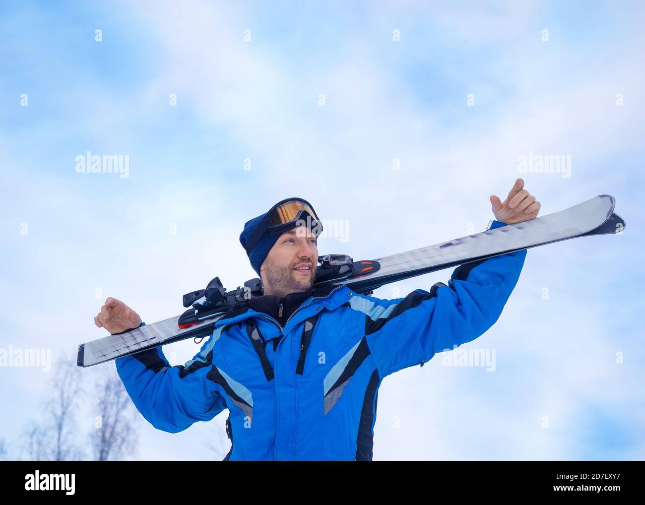 Smiling man with a ski make having rest before next downhill skiing. Man looking on the mountain. Active lifestyle and open air sports concept. Stock Photo