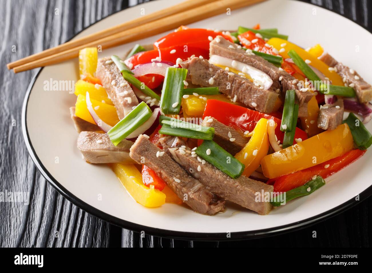stir fried of beef tongue with bell pepper, onion and sesame seeds close-up in a plate on the table. horizontal Stock Photo