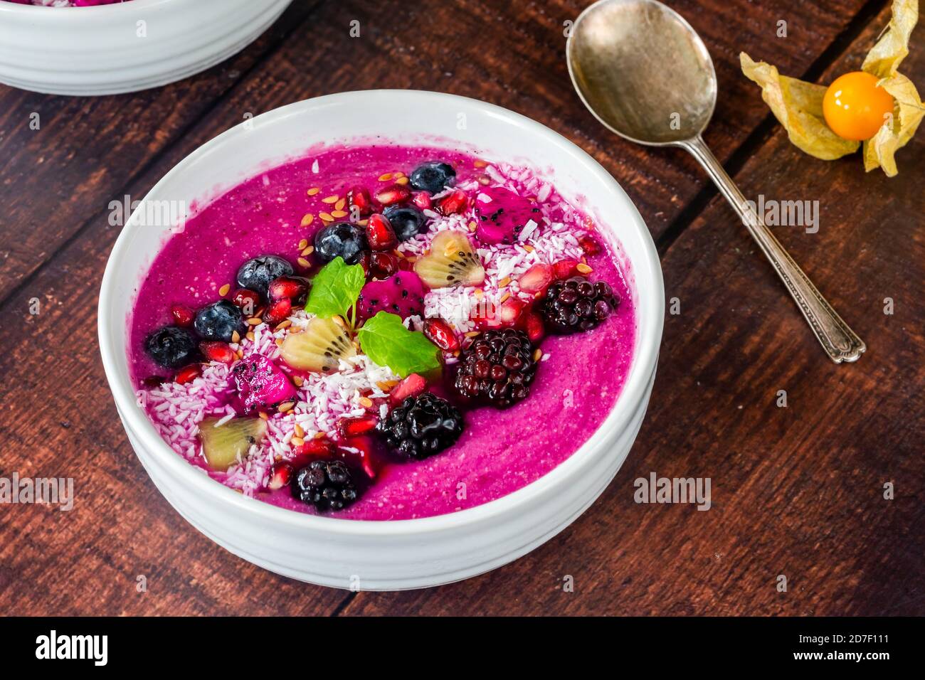 Healthy fruit breakfast pitaya bowl. Girl eating fruits smoothie sitting  outside in park for lunch break. vegan food closeup. Dragonfruit puree  Stock Photo - Alamy