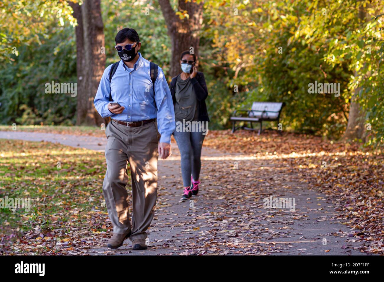 Frederick, MD, USA 10/14/2020: An Indian young professional man and an African American woman is seen walking in Baker park with face masks due to COV Stock Photo