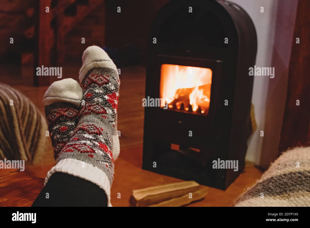 Feet in wool socks warming near fireplace in rustic cabin house. Cozy