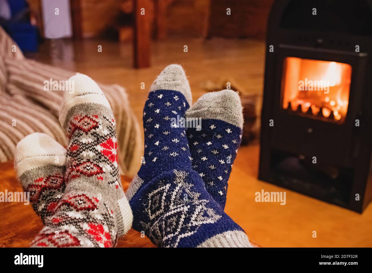 Feet in wool socks warming near fireplace in rustic cabin house. Cozy