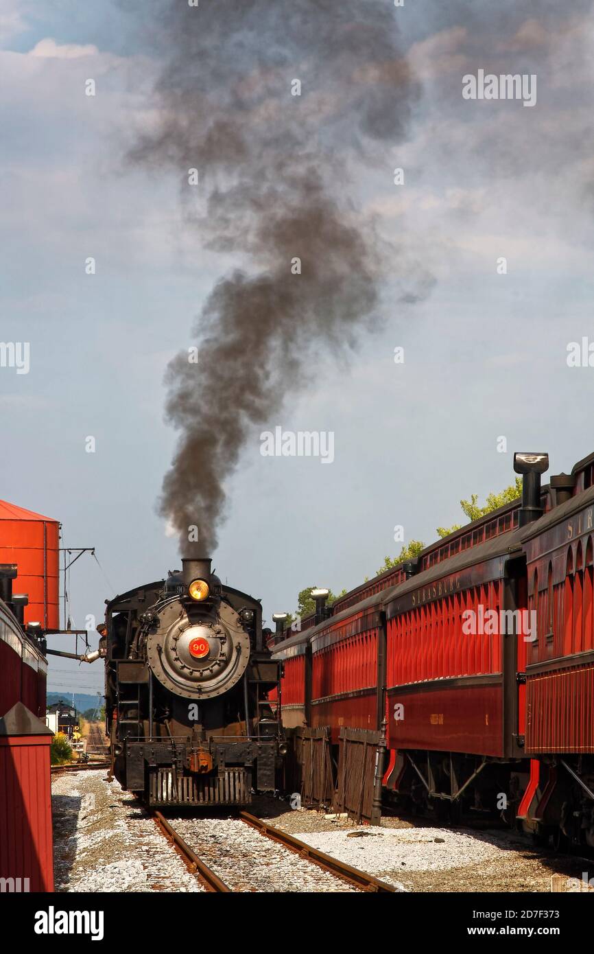 antique steam train getting water, locomotive #90, red  tank, black steam cloud, tourist ride, pullman cars alongside, transportation, Strasburg Railr Stock Photo