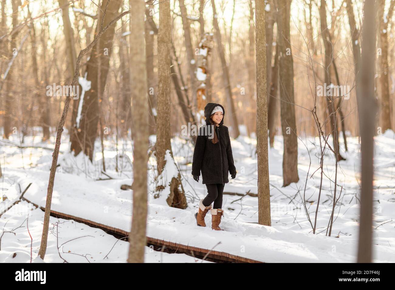 Winter people lifestyle young happy woman walking on a forest walk alone enjoying cold weather day on a active stroll in teddy jacket and shearling Stock Photo