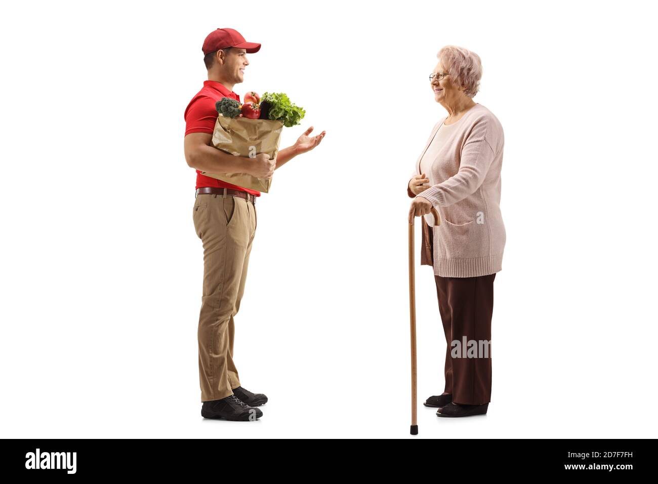 Full length profile shot of a delivery guy with a grocery bag talking to an elderly woman isolated on white background Stock Photo