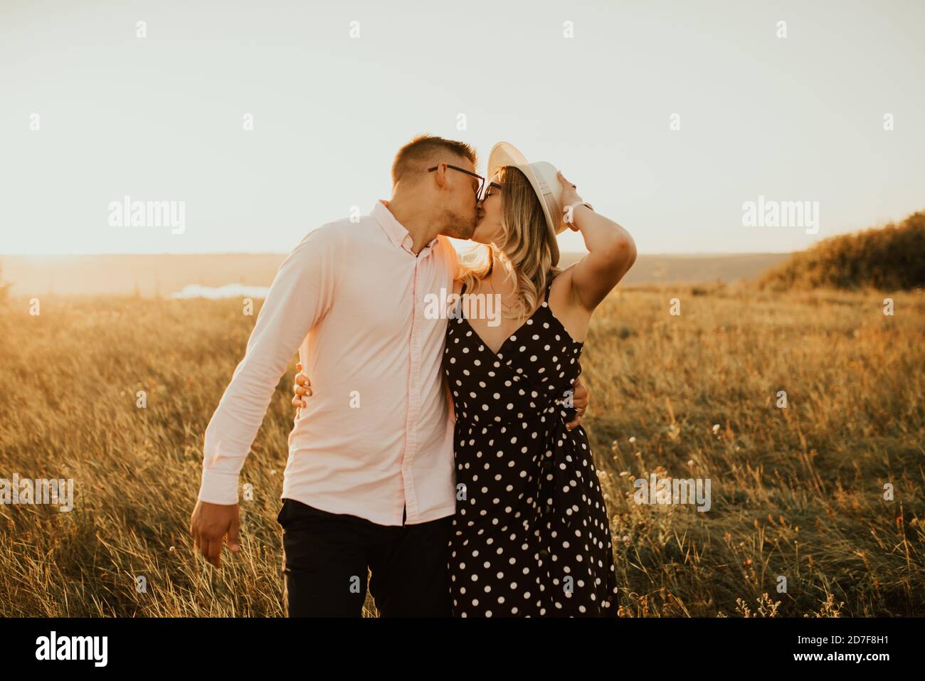 guy with a girl in hat walking in meadow Stock Photo