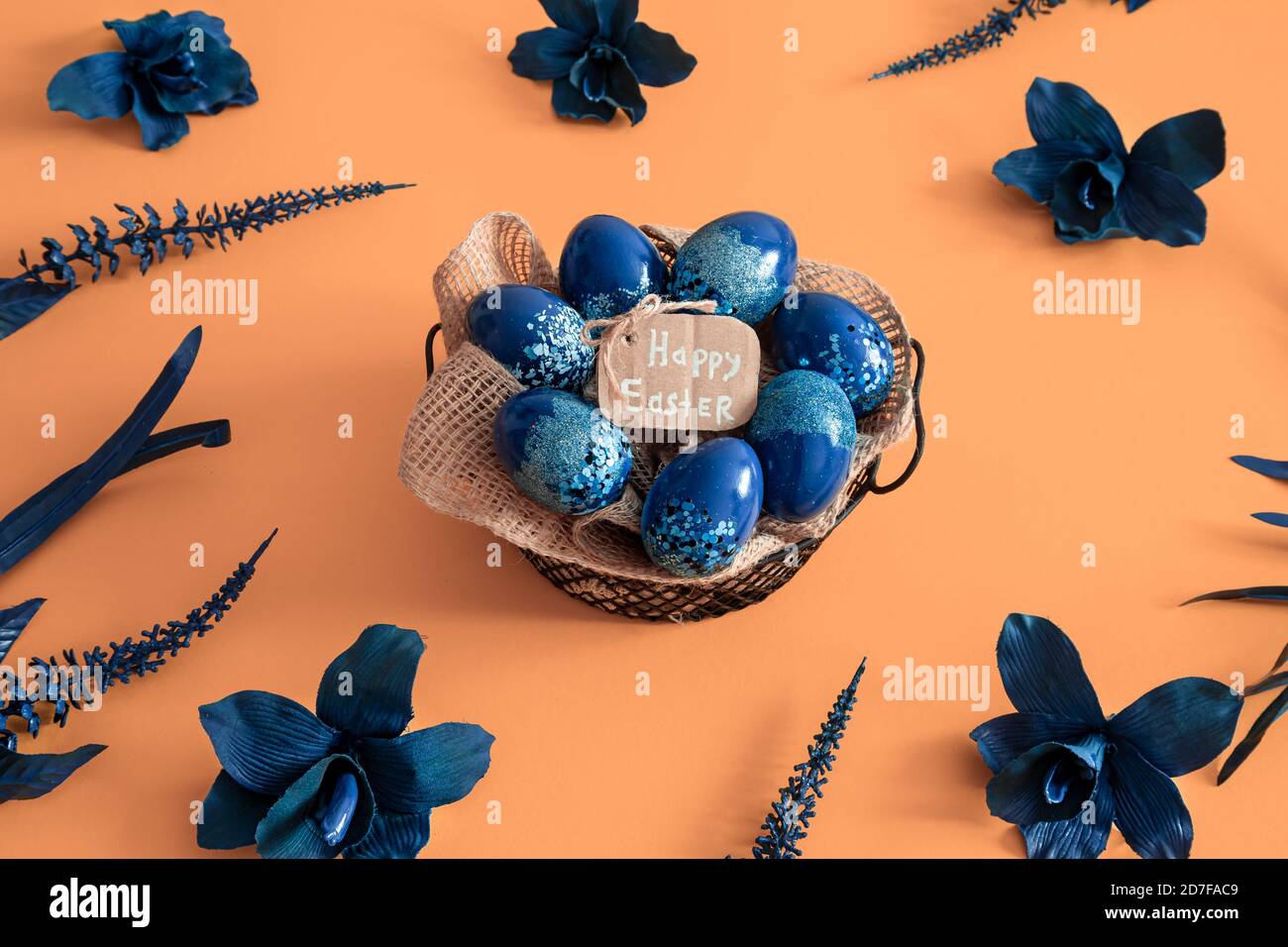 Creative Easter layout made of colorful eggs and flowers on blue ...
