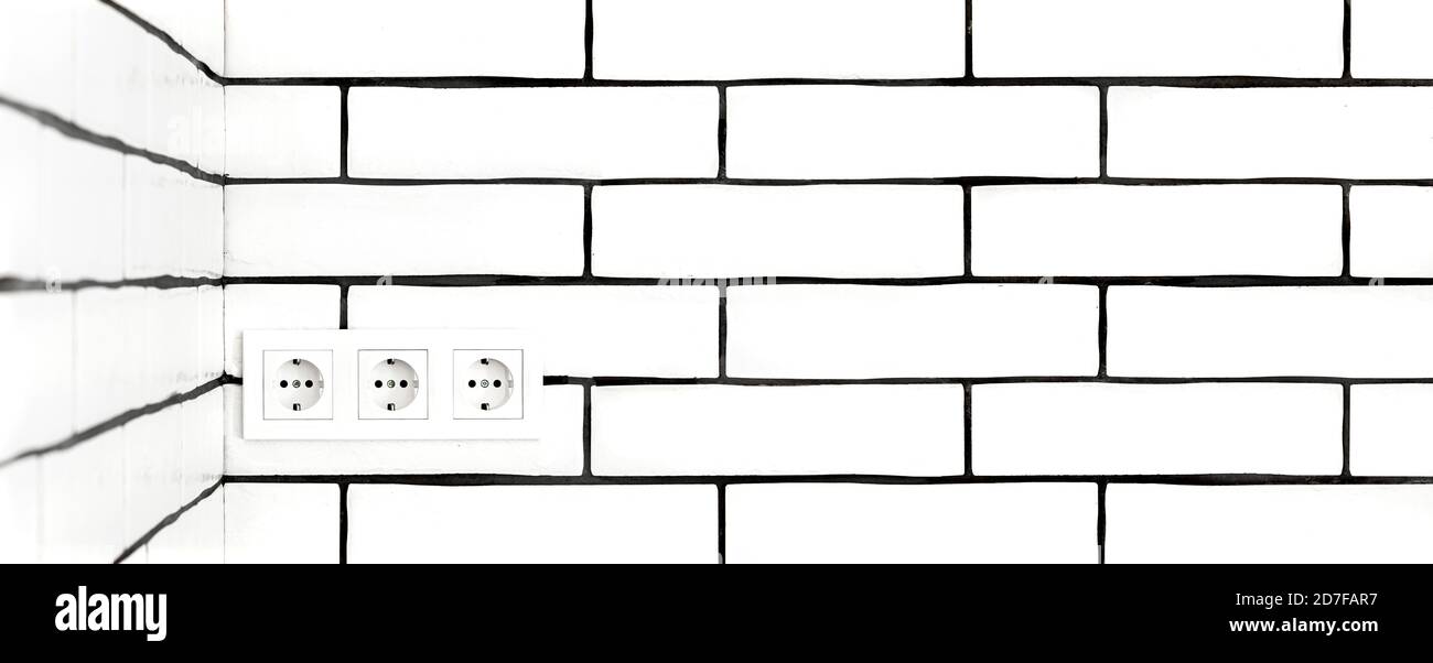 Electrical outlets against a white brick wall. Space for text. Stock Photo