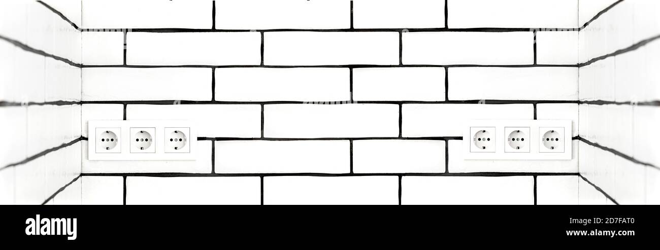 Electrical outlets against a white brick wall. Space for text. Stock Photo