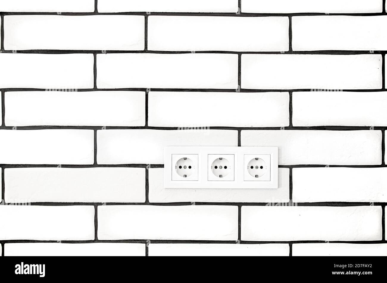 Electrical outlets against a white brick wall. Space for text. Stock Photo