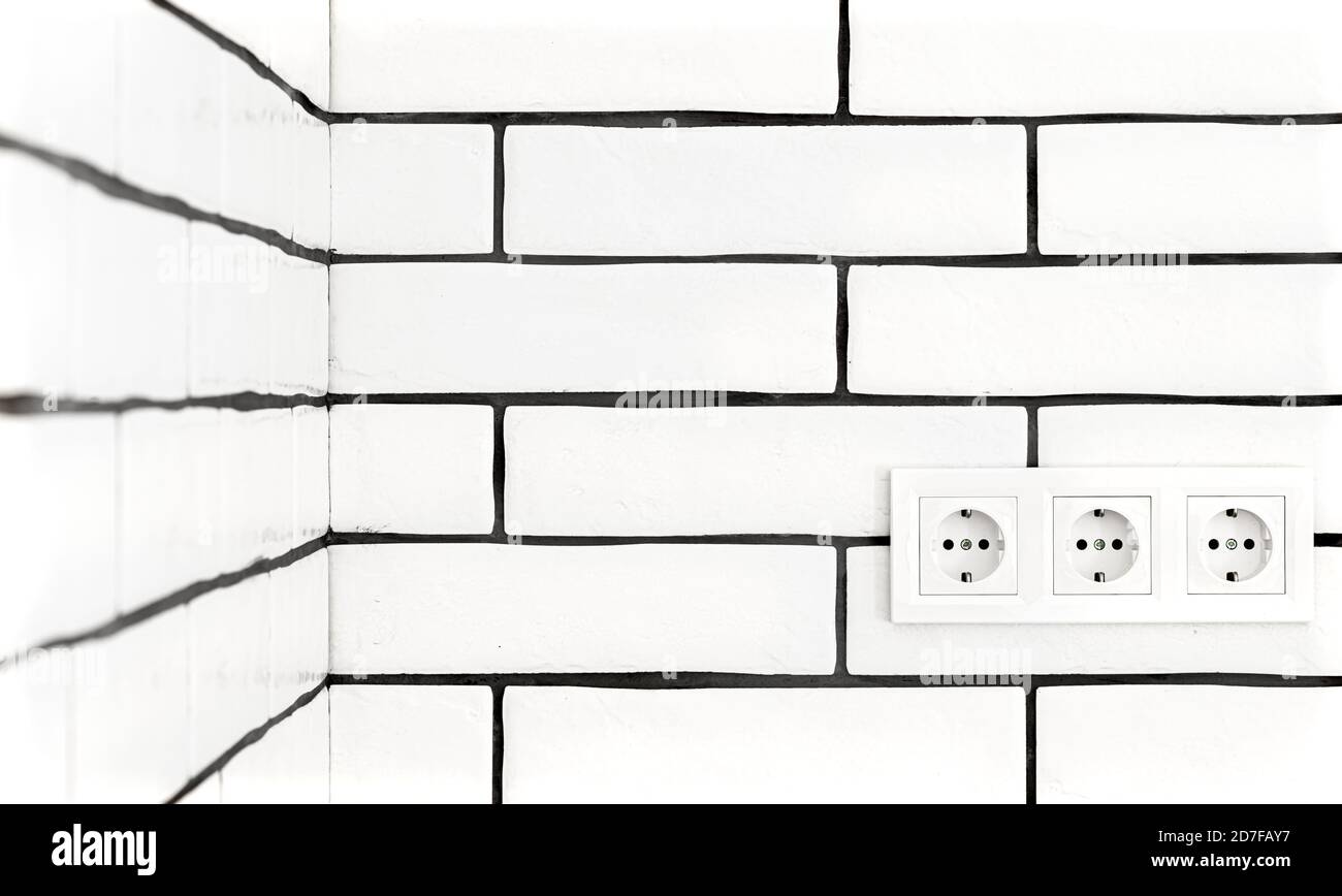 Electrical outlets against a white brick wall. Space for text. Stock Photo