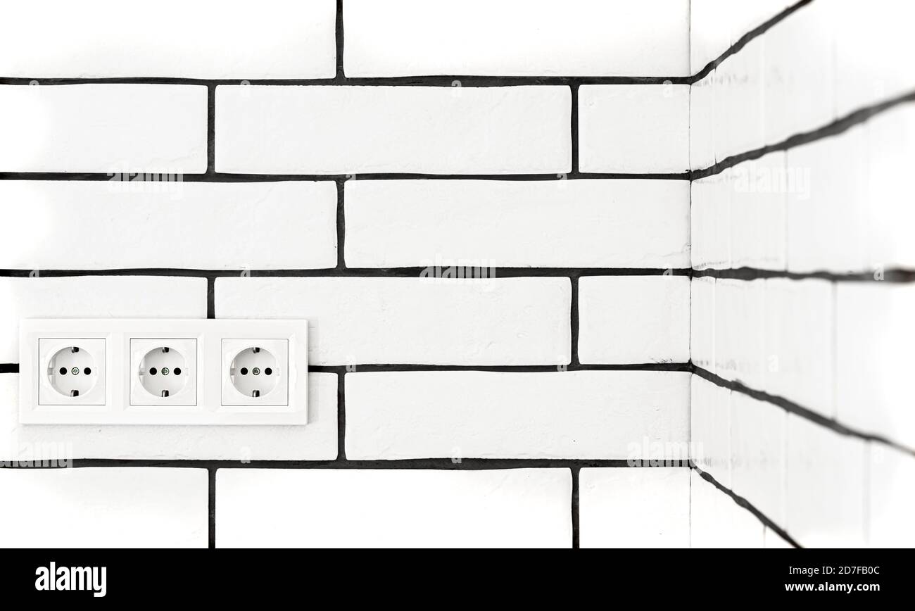 Electrical outlets against a white brick wall. Space for text. Stock Photo