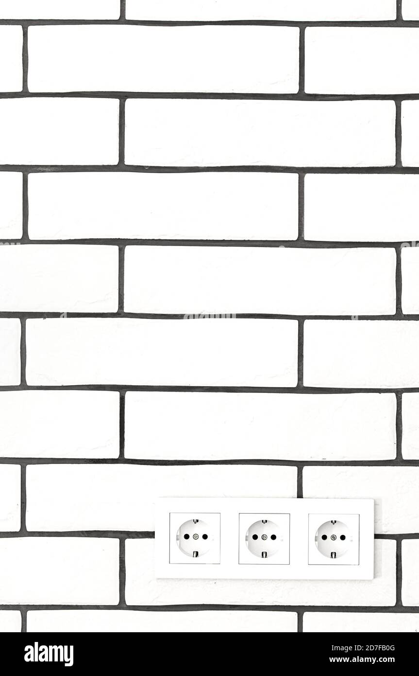 Electrical outlets against a white brick wall. Space for text. Stock Photo