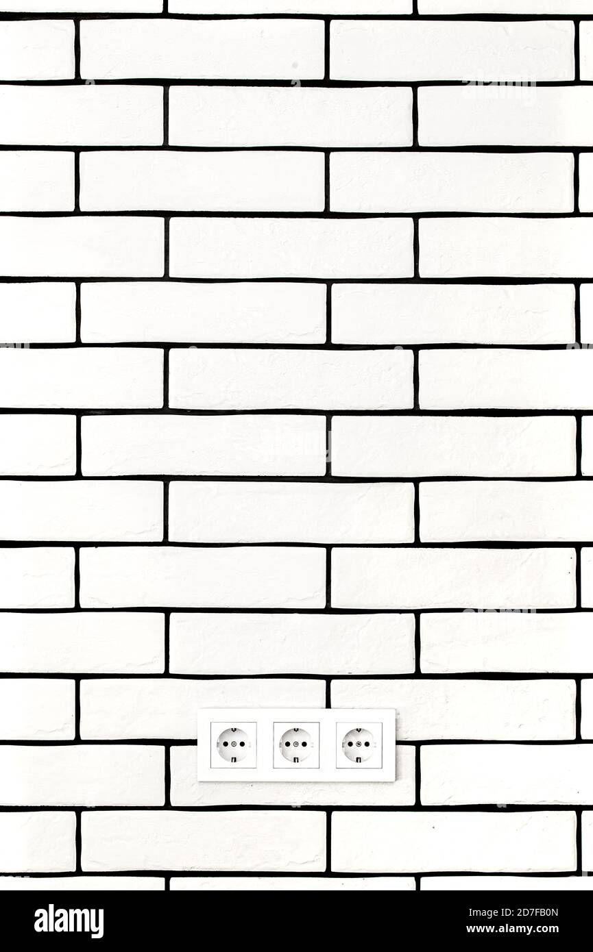Electrical outlets against a white brick wall. Space for text. Stock Photo