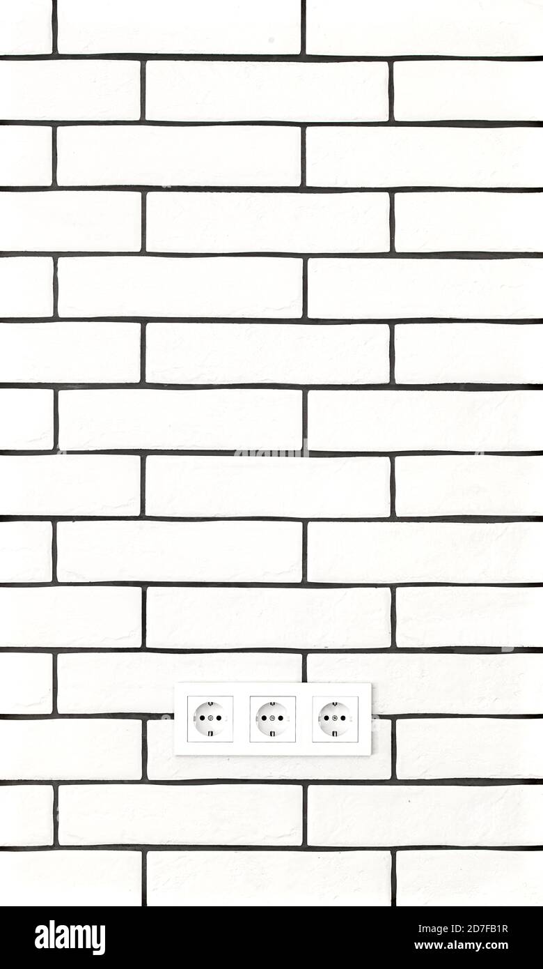 Electrical outlets against a white brick wall. Space for text. Stock Photo