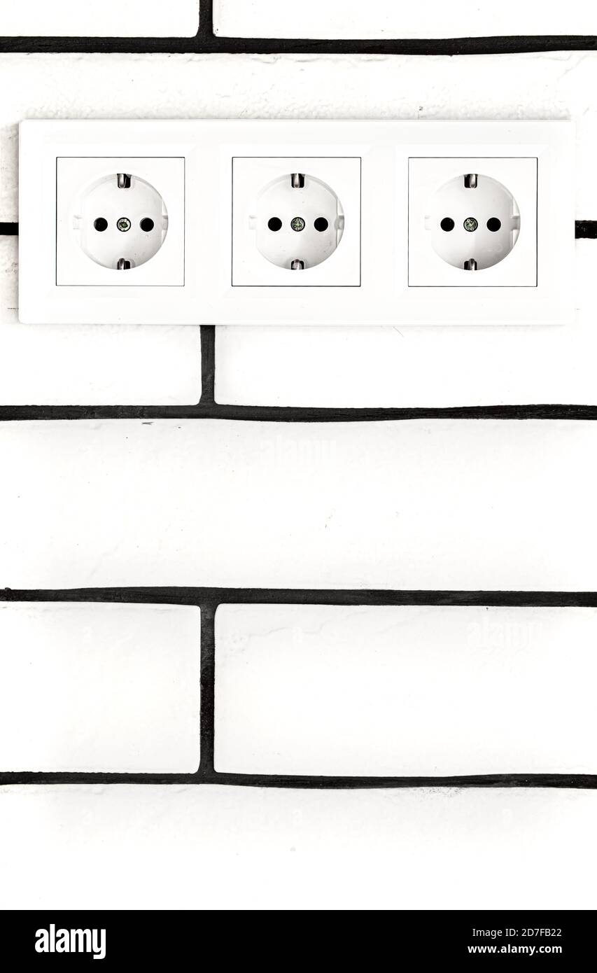 Electrical outlets against a white brick wall. Space for text. Stock Photo
