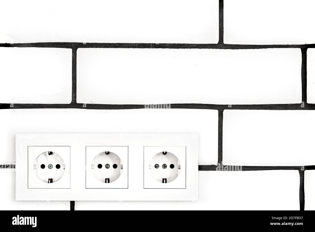 Electrical outlets against a white brick wall. Space for text. Stock Photo